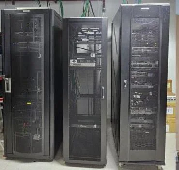Tres gabinetes de servidores y equipos de red instalados en un cuarto técnico.